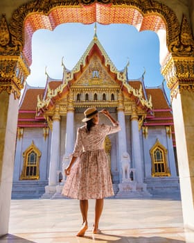 a Asian woman walking at Wat Benchamabophit temple in Bangkok Thailand, The Marble temple in Bangkok. Asian woman with a hat visiting a temple in Bangkok