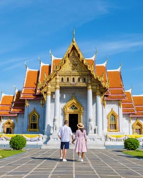 A couple of men and women visit Wat Benchamabophit temple in Bangkok Thailand, The Marble temple in Bangkok. Asian woman with a hat and European men visiting a temple in Bangkok