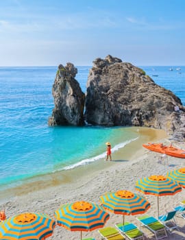 Asian women visit a Pebble beach of Monterosso Cinque Terre Italy, Chairs and umbrellas on the beach al Mare Spiaggia di Fegina beach, Monterosso, part of the Cinque Terre Italy Europe