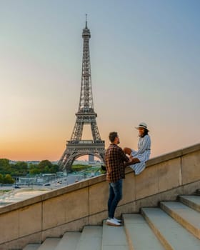 Young couple by Eiffel Tower at Sunrise, Paris Eifel Tower Sunrise man woman in love, valentine concept in Paris the city of love. Men and women visiting the Eiffel Tower Paris France.