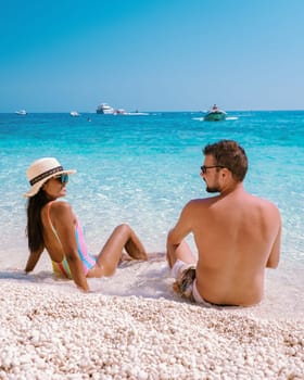 Golfo di Orosei Sardina, Men, and women on the beach Sardinia Italy, young couple vacation Sardinia Italy, couple of men and woman playing in the ocean with crystal clear blue water in Italy