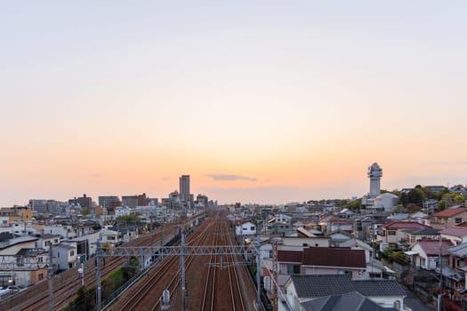 Akashi, Japan - April 19, 2023: Sunset on train tracks through neighborhood by clock tower. High quality photo