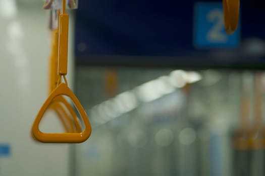 Close up and selective focus of yellow triangle handle bar in the train of MRT Jakarta, Indonesia. Blurred background with copy space.