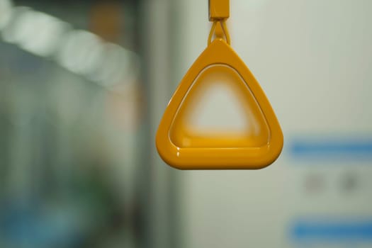 Close up and selective focus of yellow triangle handle bar in the train of MRT Jakarta, Indonesia. Blurred background with copy space.