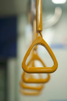 Close up and selective focus of yellow triangle handle bar in the train of MRT Jakarta, Indonesia. Blurred background with copy space.