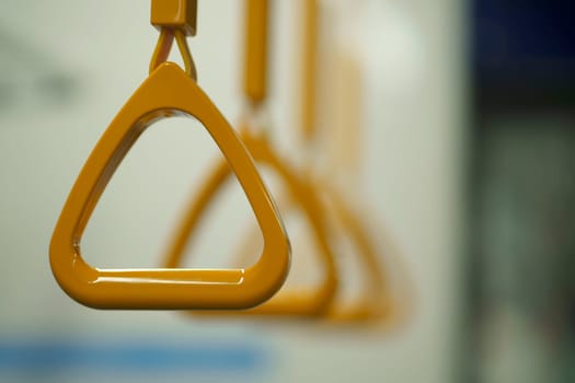 Close up and selective focus of yellow triangle handle bar in the train of MRT Jakarta, Indonesia. Blurred background with copy space.