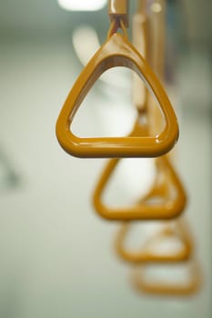Close up and selective focus of yellow triangle handle bar in the train of MRT Jakarta, Indonesia. Blurred background with copy space.