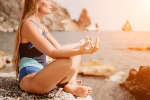 Woman sea yoga. Back view of free calm happy satisfied woman with long hair standing on top rock with yoga position against of sky by the sea. Healthy lifestyle outdoors in nature, fitness concept.