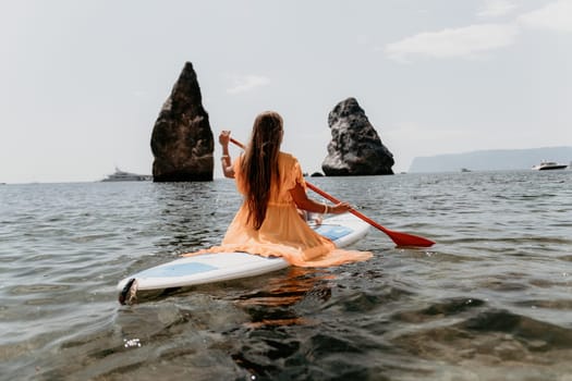 Close up shot of beautiful young caucasian woman with black hair and freckles looking at camera and smiling. Cute woman portrait in a pink bikini posing on a volcanic rock high above the sea