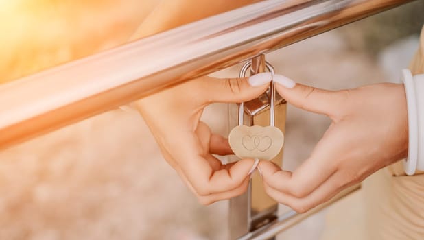 Hand, lock, heart, love, valentines day. Close up view of a woman holding a heart shaped lock that is locked onto a chain link fence.