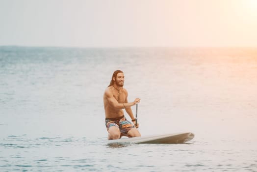 Sea woman and man on sup. Silhouette of happy young woman and man, surfing on SUP board, confident paddling through water surface. Idyllic sunset. Active lifestyle at sea or river