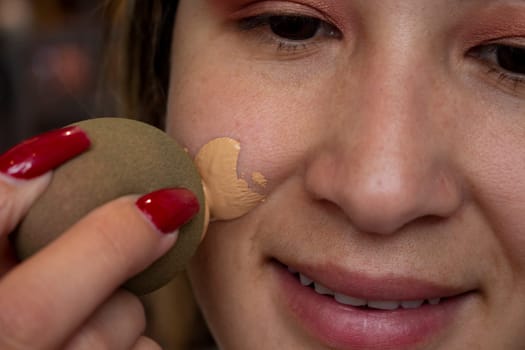 closeup of a blonde girl putting on foundation makeup with a sponge. High quality photo