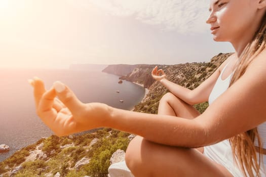 Middle aged well looking woman with black hair doing Pilates with the ring on the yoga mat near the sea on the pebble beach. Female fitness yoga concept. Healthy lifestyle, harmony and meditation.