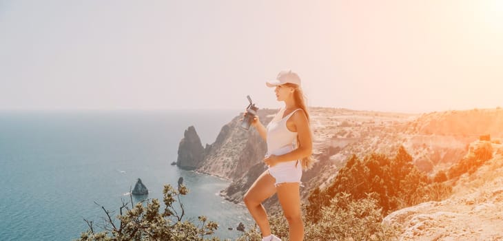 Woman travel sea. Young Happy woman in a long red dress posing on a beach near the sea on background of volcanic rocks, like in Iceland, sharing travel adventure journey