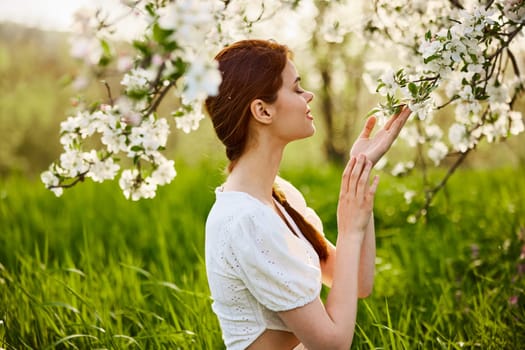 attractive fresh woman posing for a portrait of a flowering Apple tree and looks away. A vivid portrait in Sunny weather. High quality photo