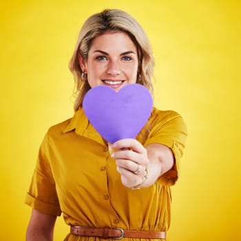 Portrait, cut out heart and woman with support, smile and wellness against a studio background. Face, female person and model with a symbol for love, paper and sign with happiness, romance and loving.