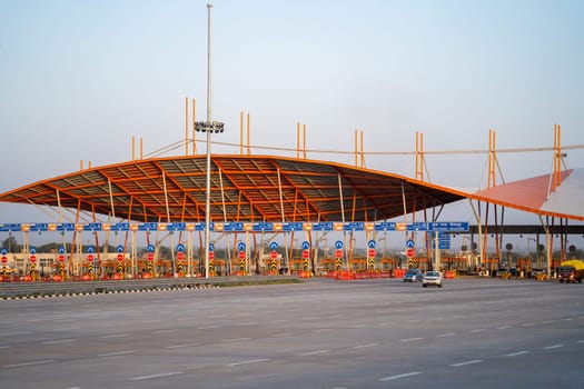 huge toll booth set up on delhi, jaipur, surat, baroda, mumbai highway with cars, trucks and other vehicles coming out after paying through FASTag RFID payment in India