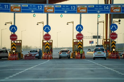 huge toll booth set up on delhi, jaipur, surat, baroda, mumbai highway with cars, trucks and other vehicles coming out after paying through FASTag RFID payment in India