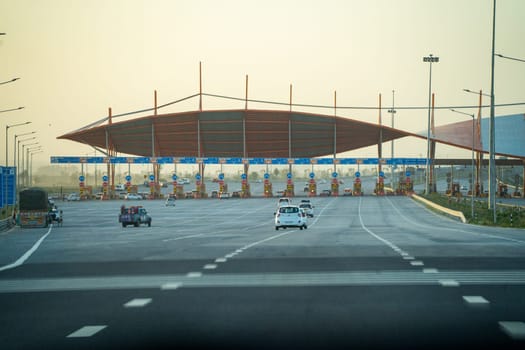 huge toll booth set up on delhi, jaipur, surat, baroda, mumbai highway with cars, trucks and other vehicles coming out after paying through FASTag RFID payment in India