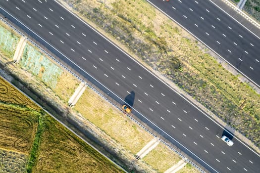 aerial drone shot moving along and shooting straight down of new delhi mumbai jaipur express elevated highway showing six lane road with green feilds with rectangular farms on the sides