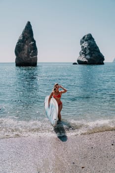 Close up shot of beautiful young caucasian woman with black hair and freckles looking at camera and smiling. Cute woman portrait in a pink bikini posing on a volcanic rock high above the sea