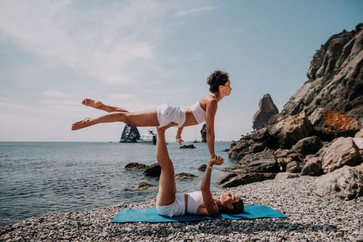 Woman sea yoga. Back view of free calm happy satisfied woman with long hair standing on top rock with yoga position against of sky by the sea. Healthy lifestyle outdoors in nature, fitness concept.