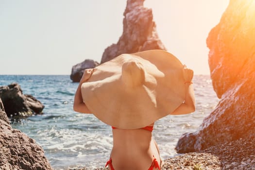 Woman travel sea. Young Happy woman in a long red dress posing on a beach near the sea on background of volcanic rocks, like in Iceland, sharing travel adventure journey