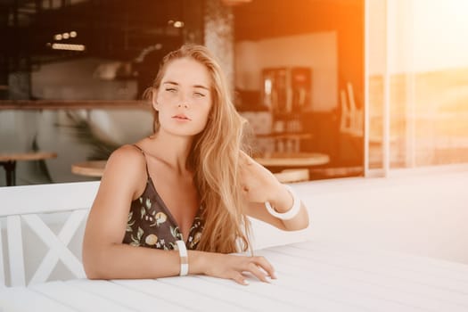 Happy woman portrait in cafe. Boho chic fashion style. Outdoor photo of young happy woman with long hair, sunny weather outdoors sitting in modern cafe