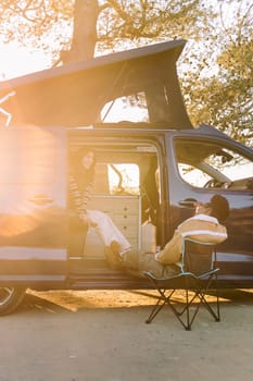 two young women chatting and having fun in a camper van at sunset, concept of travel adventure and weekend getaway with best friend