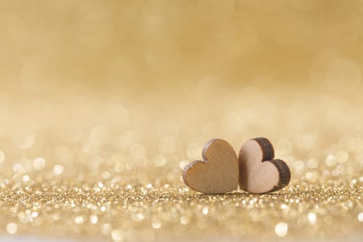 Two small handmade glitter hearts on bright golden lights bokeh background Valentines day card