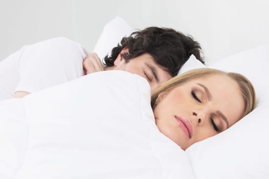 Young cute couple sleeping together in bed