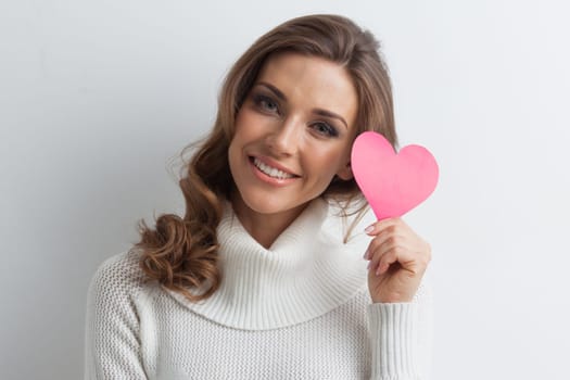 Happy young smiling woman with pink paper heart