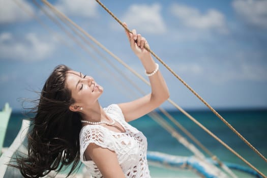 Summer travel on the yacht. Young happy woman on boat deck enjoy wind sailing the sea