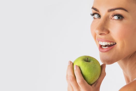 Beautiful smile, white strong teeth. Young woman with snow-white smile holding green apple