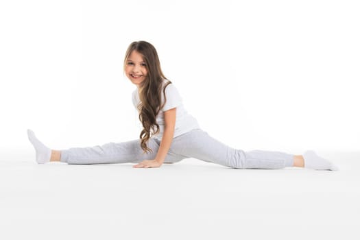 Little cute girl sitting in the splits, isolated on white background