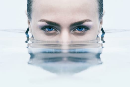 Closeup face of woman in the water, blue eyes