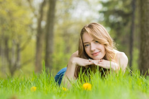 Pretty woman lying down on dandelions field happy cheerful girl resting on dandelions meadow, relaxation outdoor in springtime, vacation
