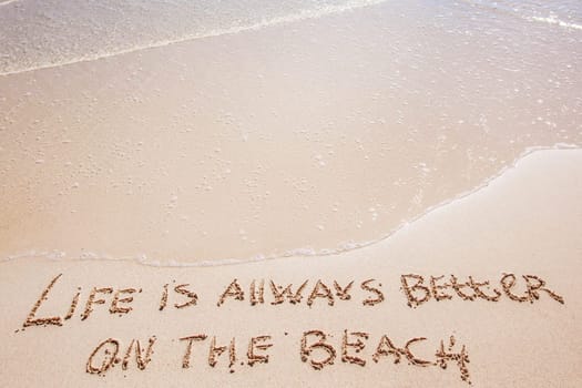 Life is always better on the beach written on the sand of tropical sea beach