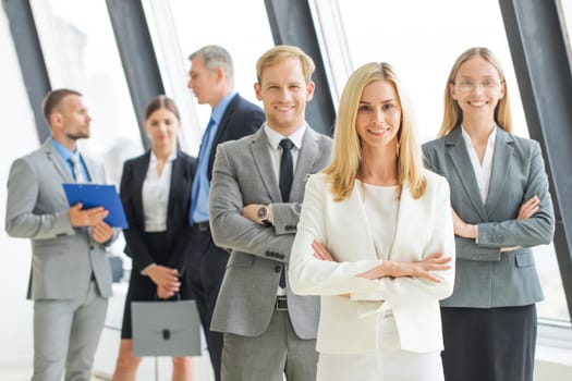 Successful business team with arms crossed at the office, woman showing ok sign
