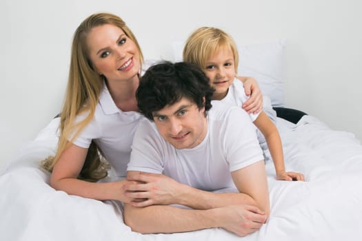 Smiling family with child wake up in bed