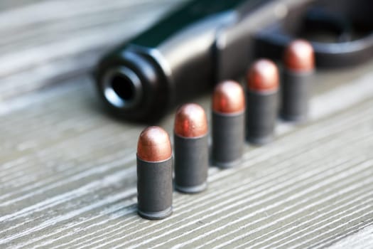 Handgun cartridges closeup on old wooden background near pistol