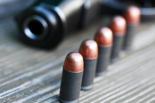 Handgun cartridges closeup on old wooden background near pistol