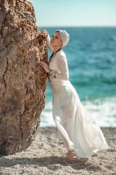 Middle aged woman looks good with blond hair, boho style in white long dress on the beach decorations on her neck and arms