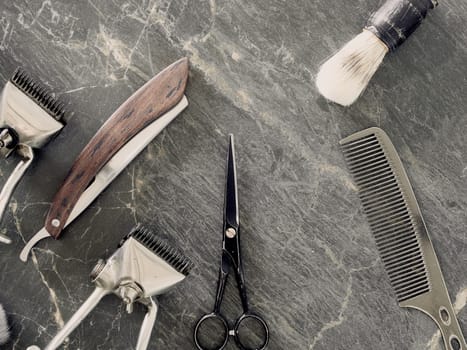 On a grey marble surface are old barber tools. Vintage manual hair clipper comb razor shaving brush shaving brush hairdressing scissors. top view. flat lay.
