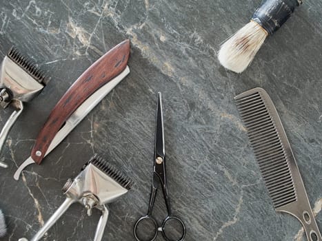 On a grey marble surface are old barber tools. Vintage manual hair clipper comb razor shaving brush shaving brush hairdressing scissors. top view. flat lay.