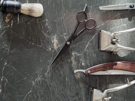 On a grey marble surface are old barber tools. Vintage manual hair clipper comb razor shaving brush shaving brush hairdressing scissors. top view. flat lay. copy space.