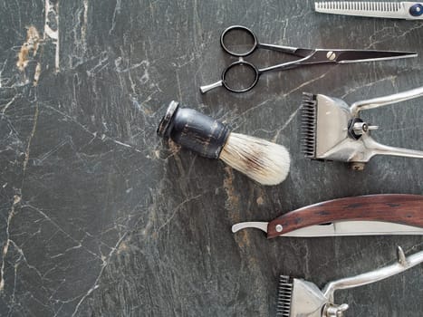 On a grey marble surface are old barber tools. Vintage manual hair clipper comb razor shaving brush shaving brush hairdressing scissors. top view. flat lay. copy space.