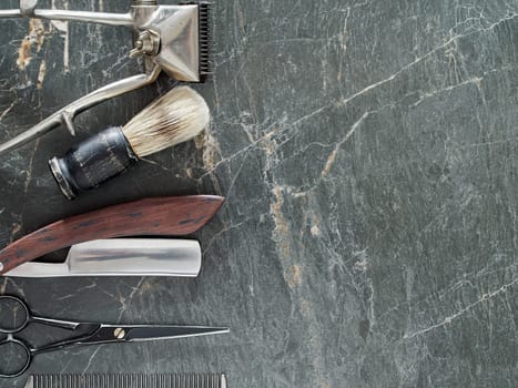 On a grey marble surface are old barber tools. Vintage manual hair clipper comb razor shaving brush shaving brush hairdressing scissors. top view. flat lay. copy space.