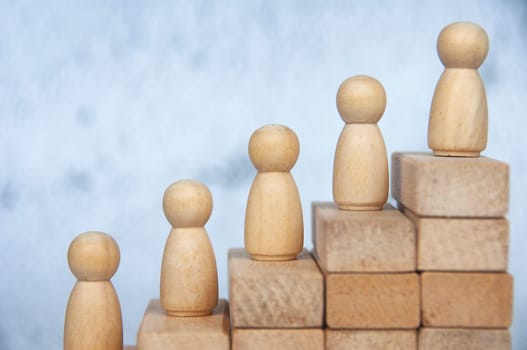 Wooden figure on top of stacking cubes representing goal achievement. Copy space, Goal achievement and leadership concept.