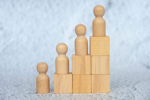 Wooden figure on top of stacking cubes representing goal achievement. Goal achievement and leadership concept